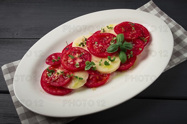 Caprese salad, Italian traditional dish, tomatoes with mozzarella cheese, basil and spices, top