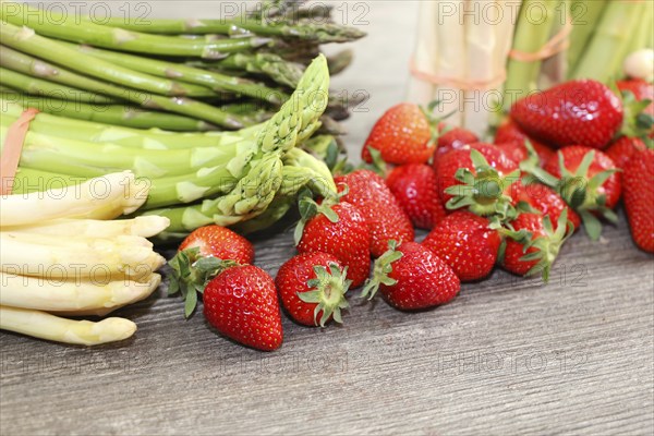 Green asparagus, white asparagus and fresh strawberries decorated on a rustic wooden table