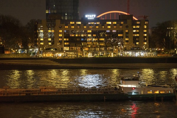 The Hyatt Regency Hotel on the Rhine, in Cologne Deutz, behind it the illuminated arch of the