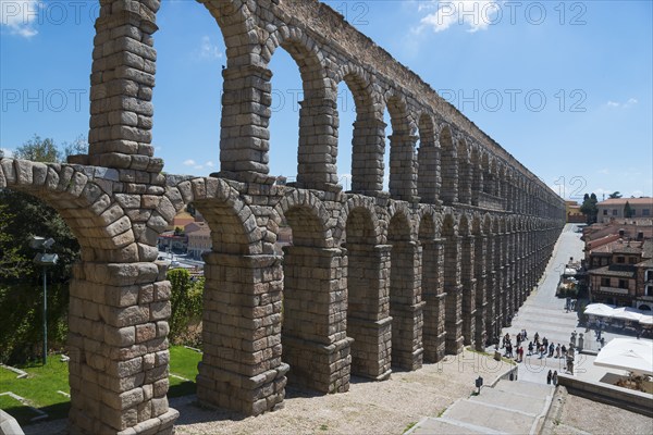 Historic aqueduct with stone arches, under a sunny sky with buildings in the background, Aqueduct,