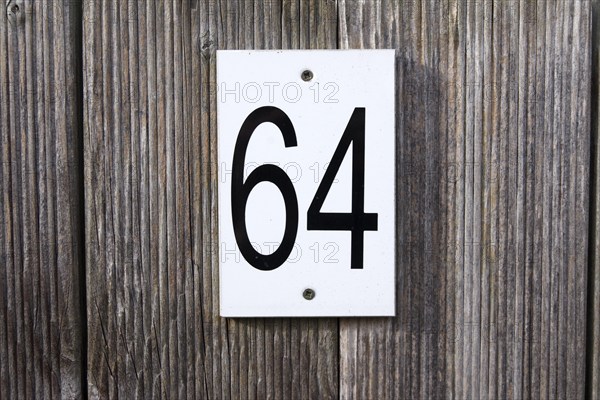 64, number, sixty-four, sign, The numbers 6 and 4 are written in black numbers on a white sign. The