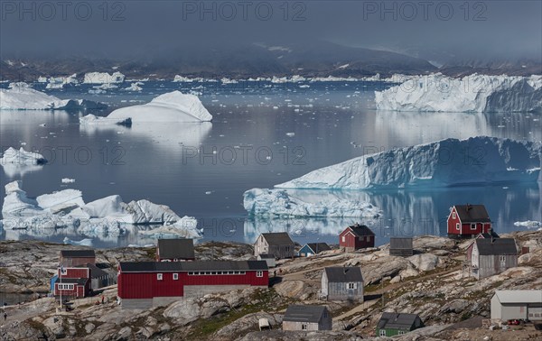 Large icebergs floating in fjord behind Inuit settlement Tiniteqilaaq, Sermilik Fjord, East