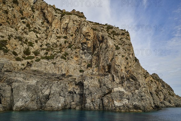 Steep cliff on the shore, light blue sky with few clouds above, boat tour Saria, Saria Island,