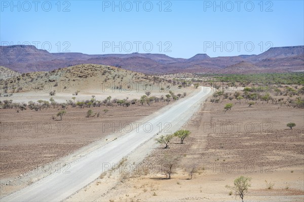 Gravel track leads through barren dry landscape with hills, Damaraland, Kunene, Namibia, Africa