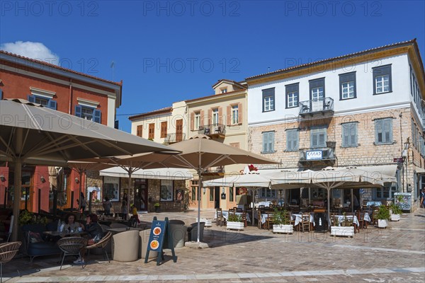 Lively street café with large parasols and colourful buildings under a blue sky, Syntagma Square,