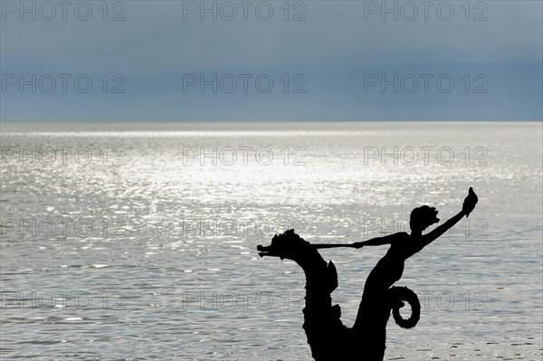 Sculpture with mermaid against the light on the promenade in Vevey on Lake Geneva, Vaud,