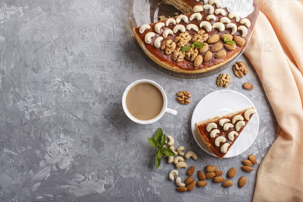Homemade cake with caramel cream and nuts with cup of coffee on a gray concrete background. top