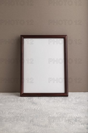 Brown wooden frame mockup on beige paper background. Blank, vertical orientation, still life, copy