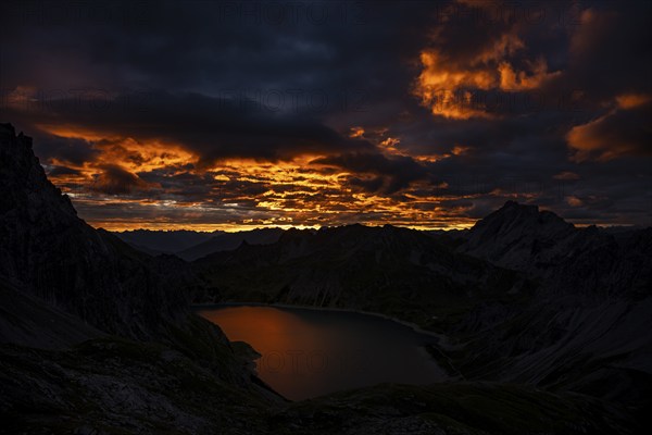 Lake Lüner See with Montafon mountains and dramatic cloudy sky at sunrise, Tschagguns, Rätikon,