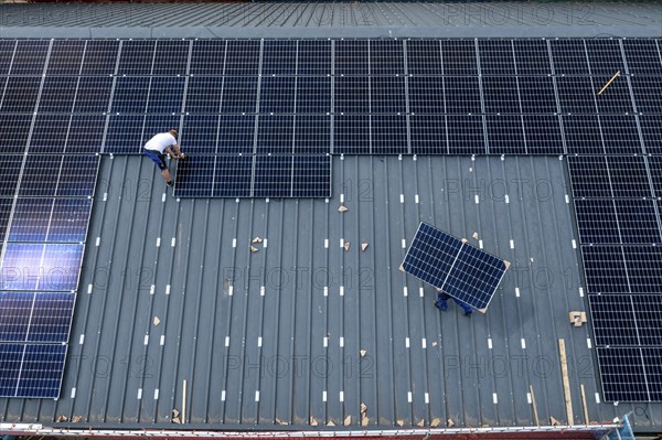 Installation of solar modules on the roof of a barn on a farm, over 210 photovoltaic modules are