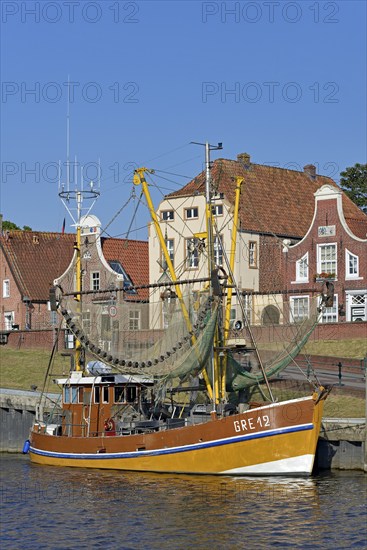Crab cutter in the harbour in front of historic buildings, blue sky, Greetsiel, North Sea, Lower