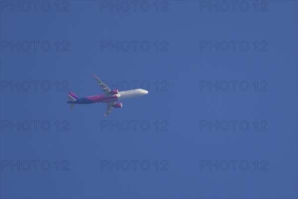 Airbus aircraft of Wizz air airlines flying across a blue sky, England, United Kingdom, Europe