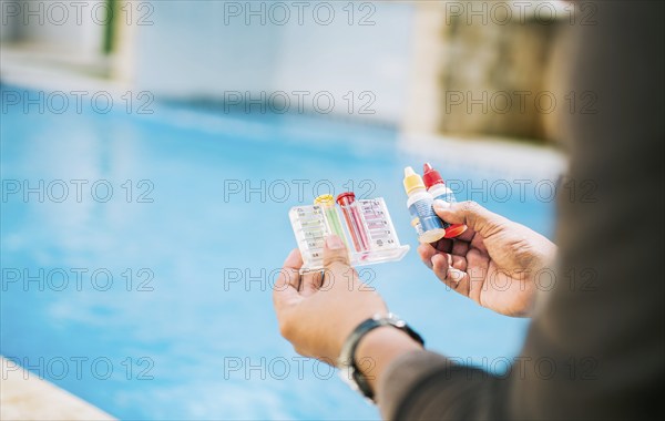 Person testing the PH of the swimming pool. Hand holding tester kit to measure chlorine and ph in