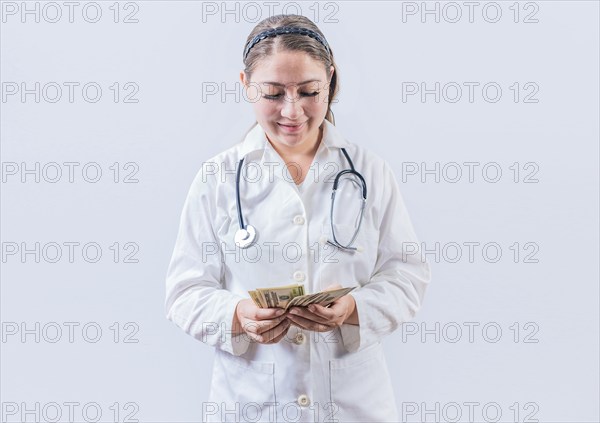 Corrupt female doctor counting money isolated. Female doctor counting banknotes on white background