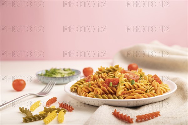 Tortiglioni semolina pasta with tomato and microgreen sprouts on a white and pink background and