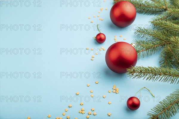 Christmas or New Year composition. Decorations, red balls, fir and spruce branches, on a blue paper