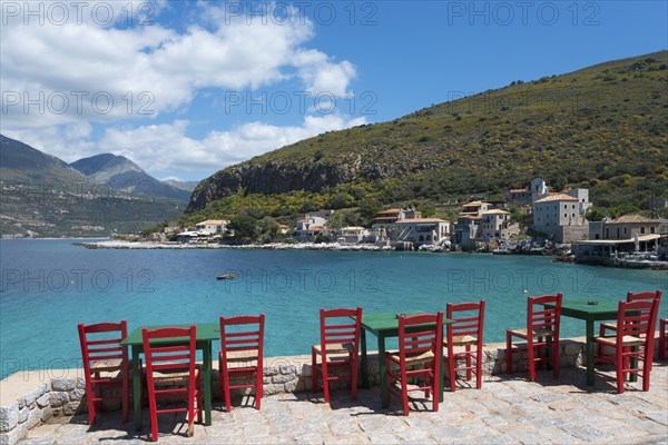 Empty red chairs on a sunny day on the shore of a calm blue sea, Limeni, Areopoli, Laconia,