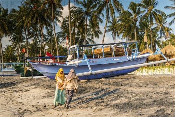 Muslim woman in the evening sun at Mangsit beach in Sengiggi, boat, fishing boat, palm beach,