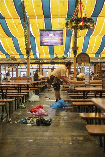 Employees cleaning the marquee after an event, rubbish scattered on the floor, Canstatter Wasen,