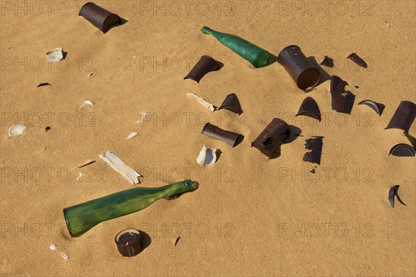 Broken glass bottles and rubbish on sand showing pollution in a desert, Matruh, Great Sand Sea,