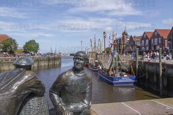 Sculpture of old and young fishermen at the cutter harbour Neuharlingersiel, East Frisia, Lower