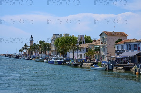 Coastal town with colourful houses, boats in the water and a lighthouse in the background on a