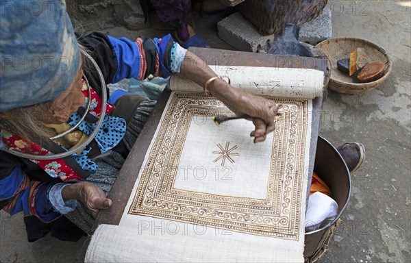 Vietnamese woman from the Hmong minority draws a pattern on linen fabric, Lung Tam linen weaving