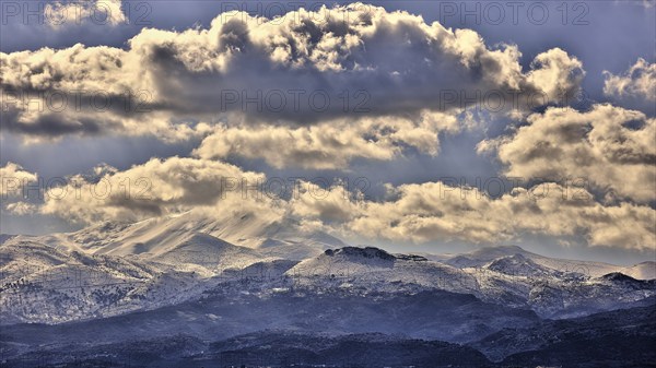 Dramatic landscape with snow-capped mountains and clouds in the blue sky with purple tones, Lefka
