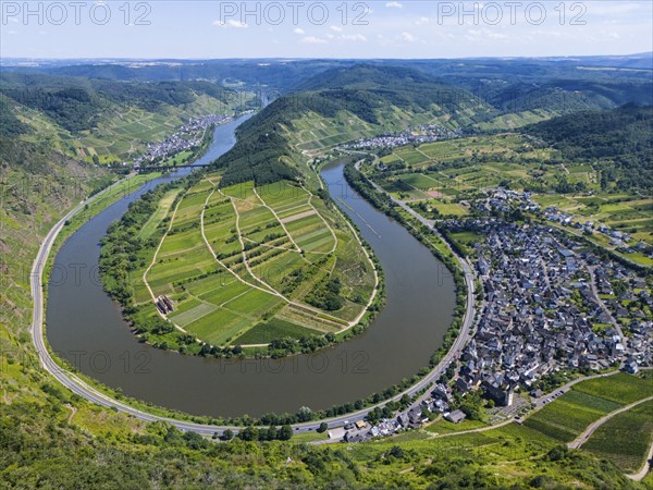 A river meanders through a green, hilly landscape with vineyards and a neighbouring village,
