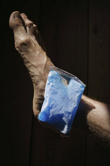 Symbolic photo on the subject of cooling for joint pain. A cooling pad is placed on an ankle and