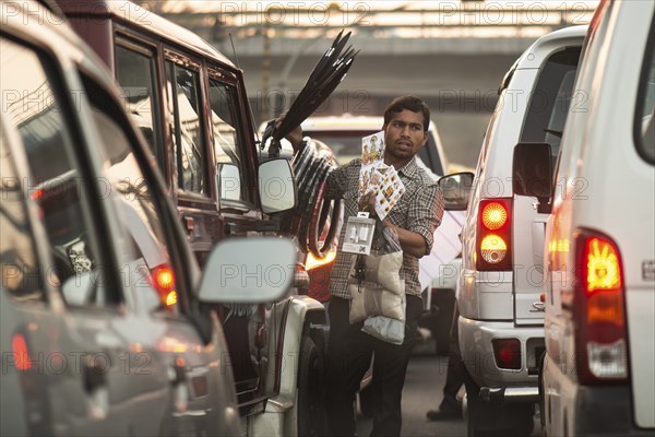 Street vendor standing between waiting cars, New Delhi or New Delhi, India, Asia