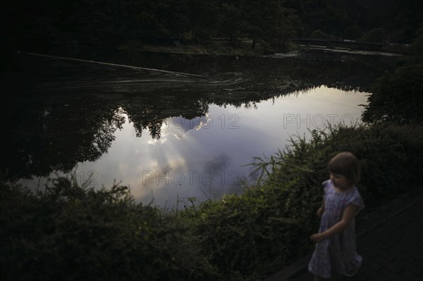 Symbolic photo on the subject of dangers on the water for small children. A little girl runs along