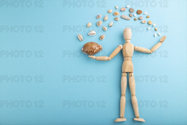 Wooden mannequin juggling sea shells on blue pastel background. copy space, isolated, travel,