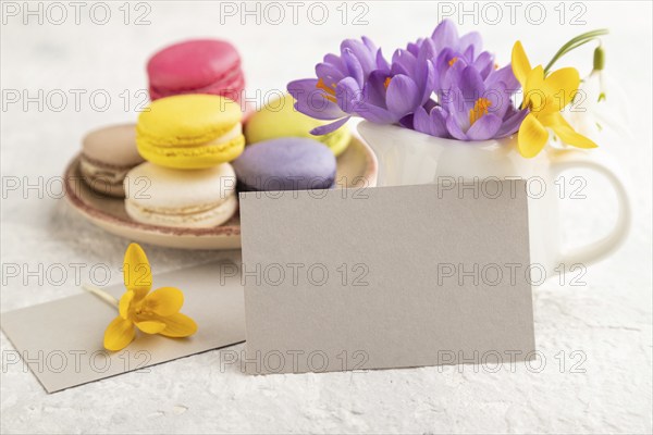 Gray paper business card mockup with spring snowdrop crocus flowers and multicolored macaroons on