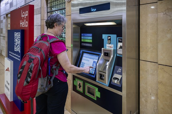 Interior shot, elderly woman, best ager at ticket machine, ticket terminal, Al Ras Station, train
