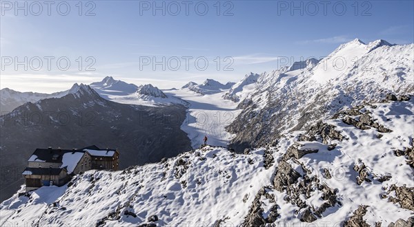 Mountaineer in front of mountain panorama and glacier, in the morning light, mountain hut
