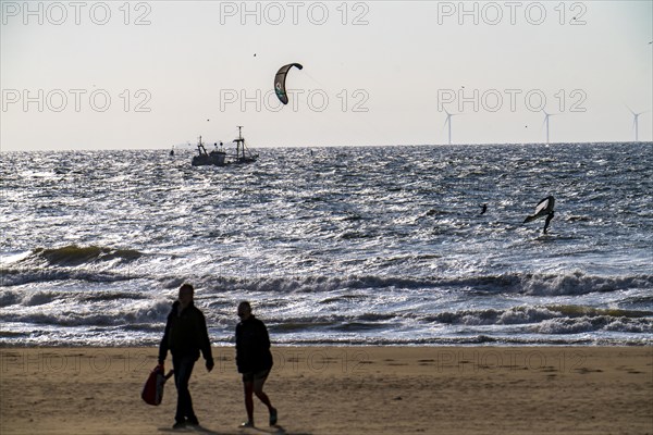 Kitesurfers and shrimp boats off the coast of Scheveningen, walkers on the beach, The Hague,