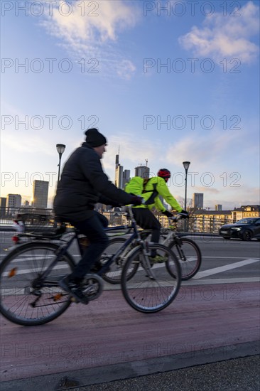 Skyline of the city centre of Frankfurt am Main, cyclist on the Ignatz-Bubis-Bridge, dusk, river
