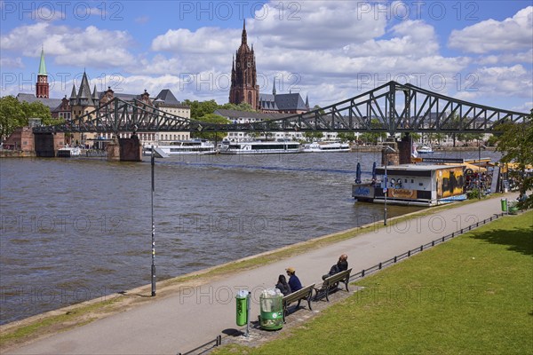 Iron footbridge with Main, riverside promenade and St Bartholomew's Cathedral in Frankfurt am Main,
