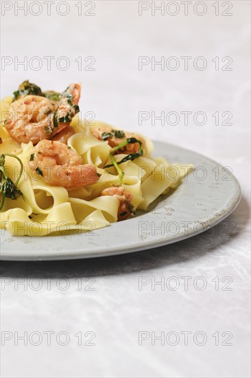 A serving of shrimp fettuccine garnished with fresh herbs is elegantly presented on a gray plate,