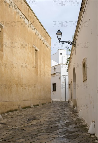 Narrow, cobbled alleyway between sand-coloured and white buildings with nostalgic alleyway