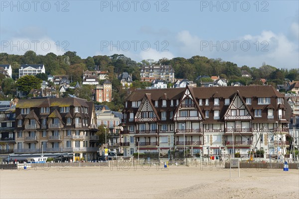 Traditional half-timbered houses in a coastal town in front of a wooded hill, Trouville-sur-Mer,