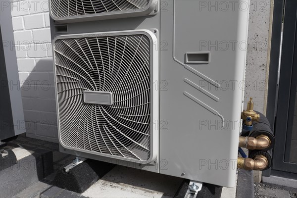 Outdoor units of a heat pump in front of a newly built two-family house, heating and air