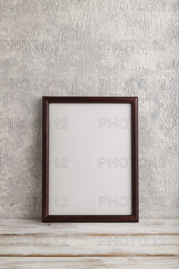 Brown wooden frame mockup on gray concrete background. Blank, vertical orientation, still life,