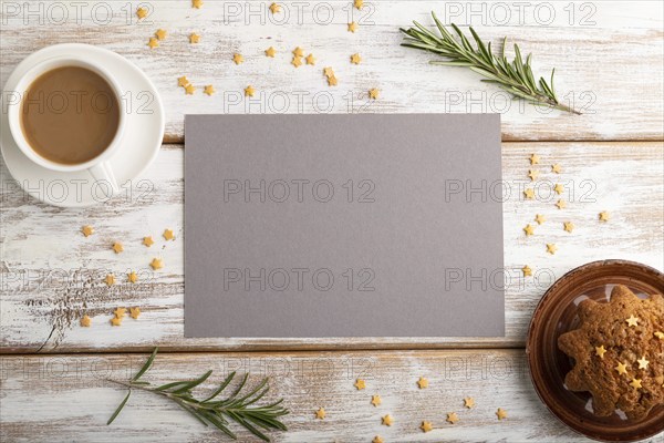 Gray paper sheet mockup with cup of coffee and cake on white wooden background. Blank, top view,