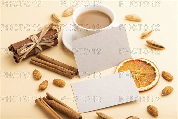 Composition of gray paper business cards, almonds, cinnamon and cup of coffee. mockup on orange