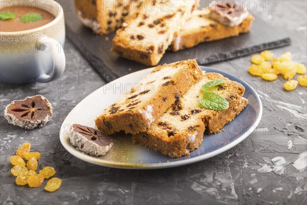 Homemade cake with raisins, dried persimmon and a cup of hot chocolate on a black concrete