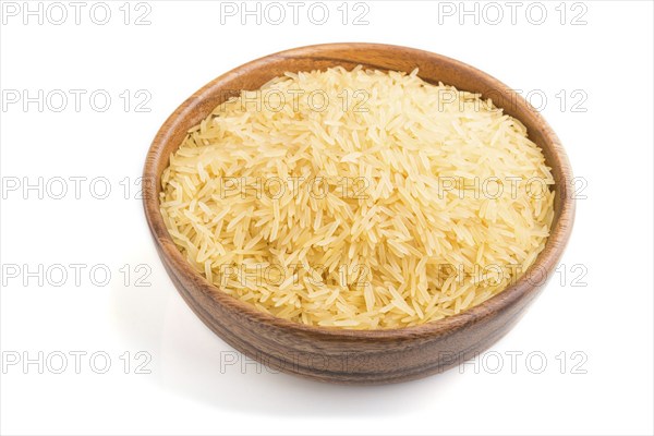 Wooden bowl with raw golden rice isolated on white background. Side view, close up