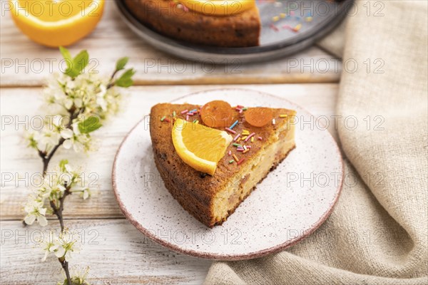 Orange cake and a cup of coffee on a white wooden background and linen textile. Side view, close