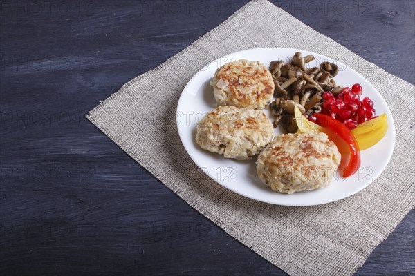 Meatballs with rice mushrooms, sweet peppers and pomegranate seeds on black wooden background.
